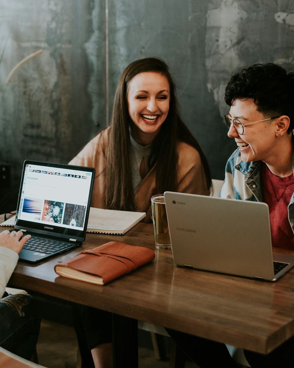 Dos personas sonríen frente a una laptop durante una sesión de trabajo